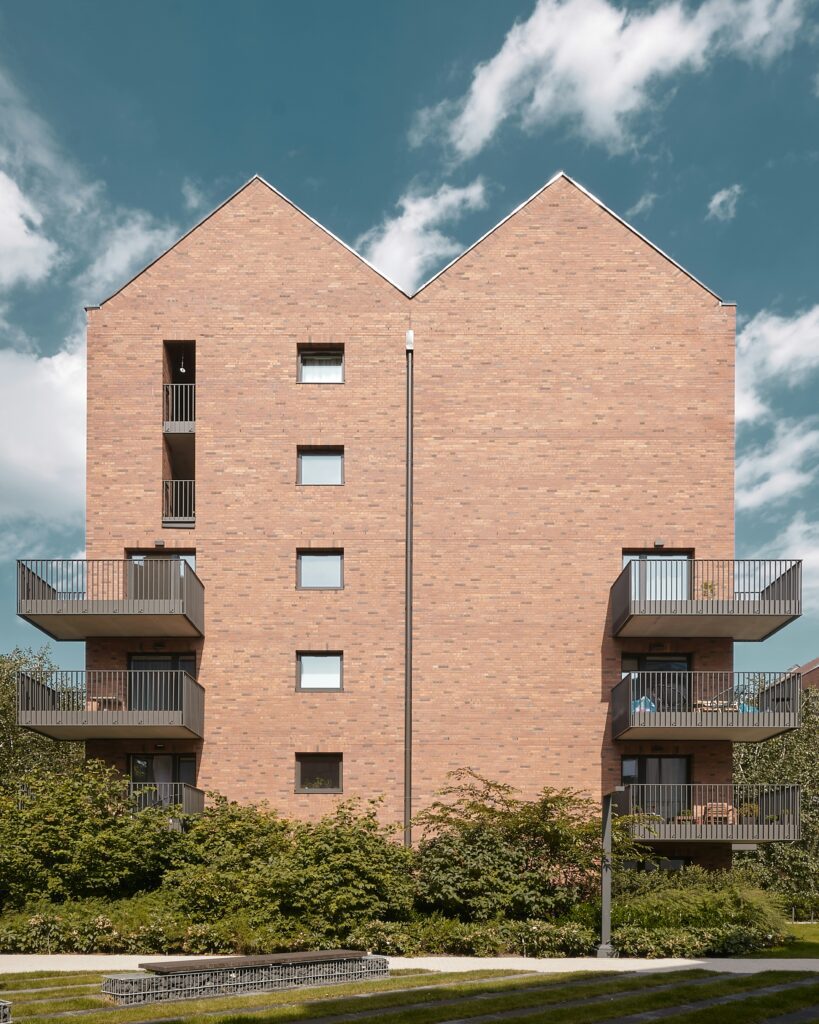 Fachada de Empreendimento Multifamily com revestimento em tijolos e varandas voltadas para área verde, ilustrando o crescimento do mercado de locação residencial no Brasil.